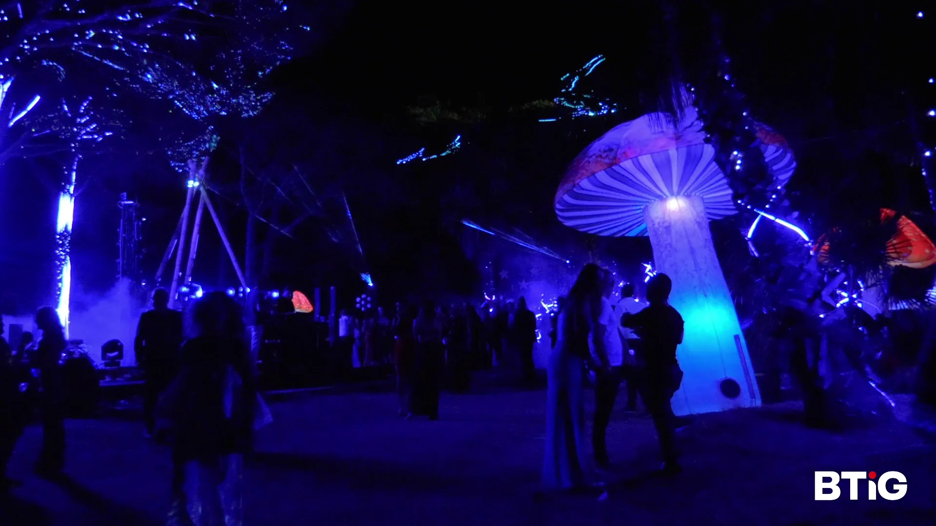 Outdoor event with illuminated mushroom sculptures and blue lighting