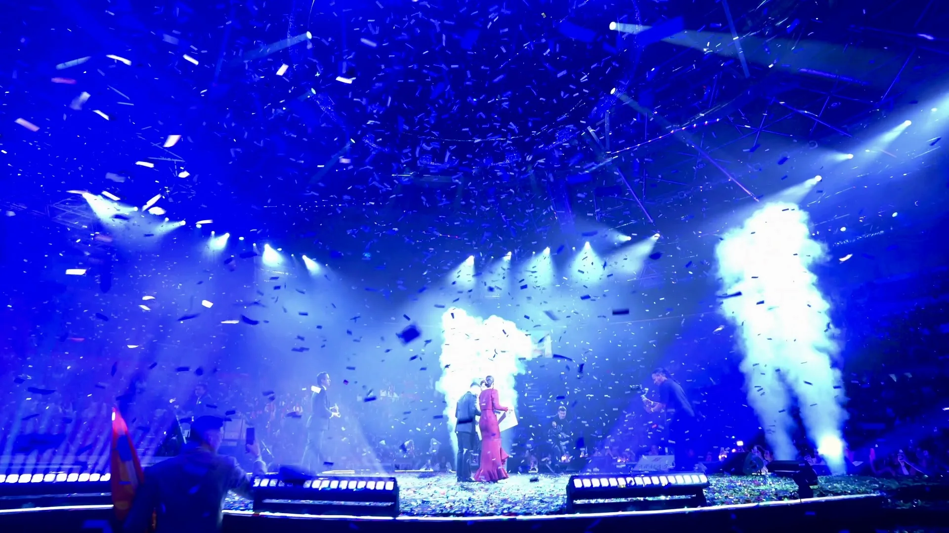 Live celebration with blue stage lighting and confetti
